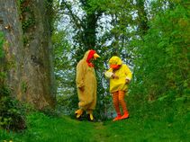 Zwei Personen in einem Waldstück, verkleidet als Huhn und Küken, unterhalten sich in fröhlicher Atmosphäre.