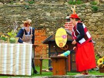 Zwei als Osterhasen verkleidete Frauen bei einer Aufführung im Freien auf Burg Ranis vor einer kleinen Dekokulisse mit Tisch, Blumen und Osterdekoration.