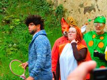 Gruppe von verkleideten Personen: ein Mann mit Strickjacke und Perücke, eine Frau im Eichhörnchenkostüm, dahinter ein Fuchs und eine Raupe.