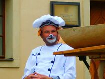 Ein Mann in Kochkostüm mit geschminktem Hasengesicht sitzt auf Burg Ranis.